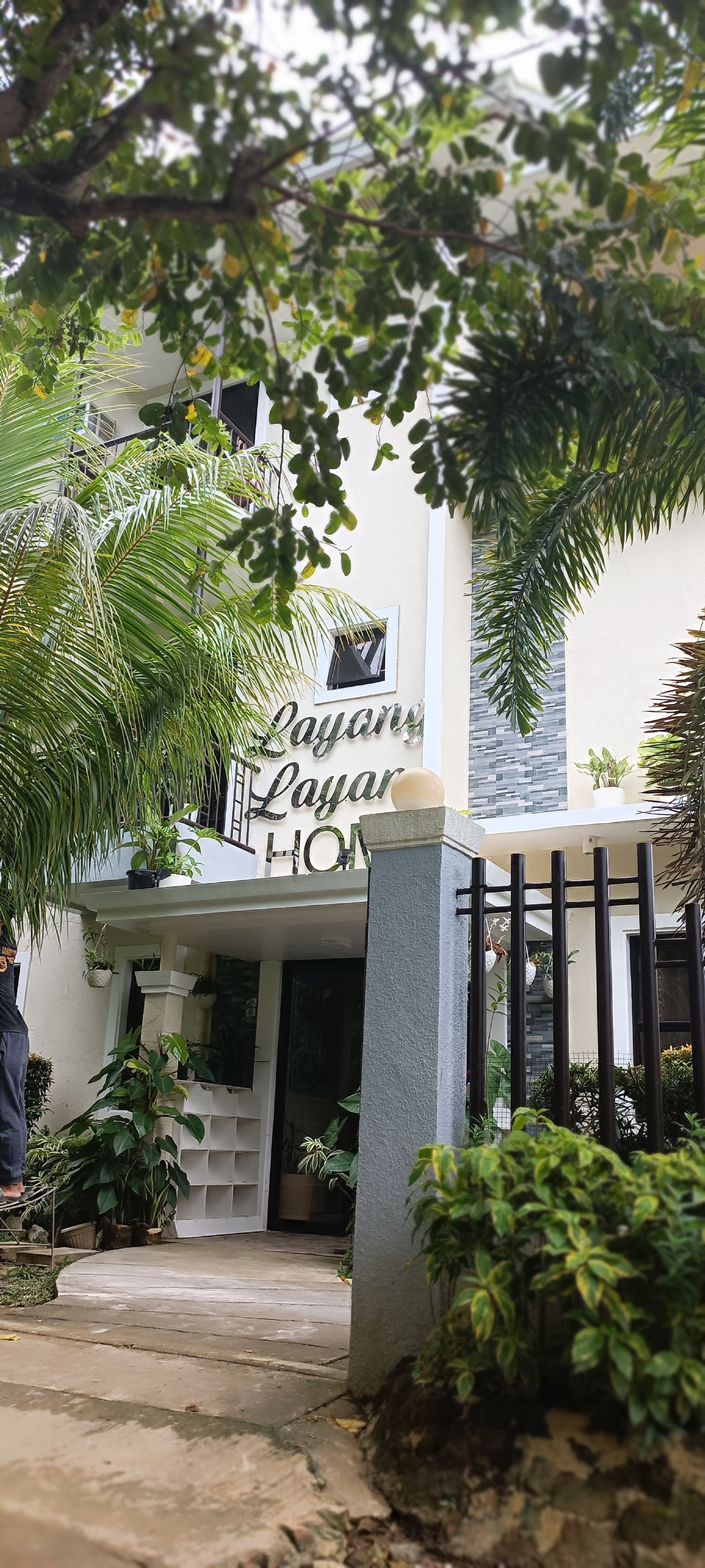 A white building with a fence and trees in front of it.