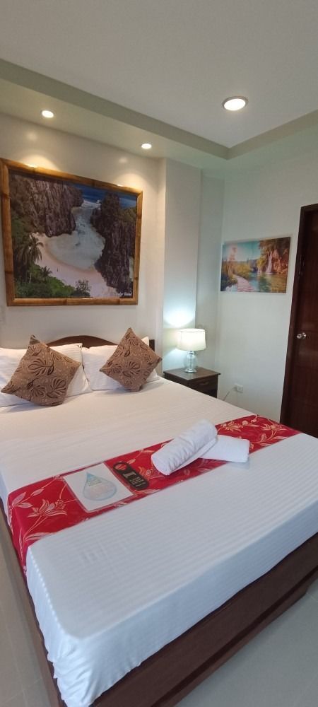 A bedroom with a large bed and a painting on the wall.