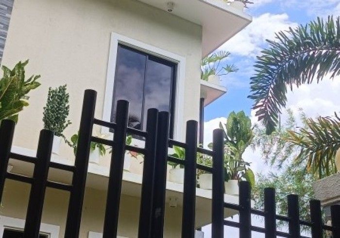 A fence surrounds a house with a palm tree in the background