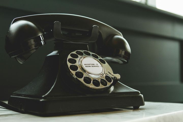 An old black telephone is sitting on a table.