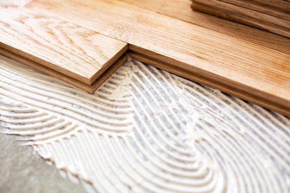 A Close up Of a Wooden Floor Being Installed with Glue — Budget Timbers in Murwillumbah, NSW