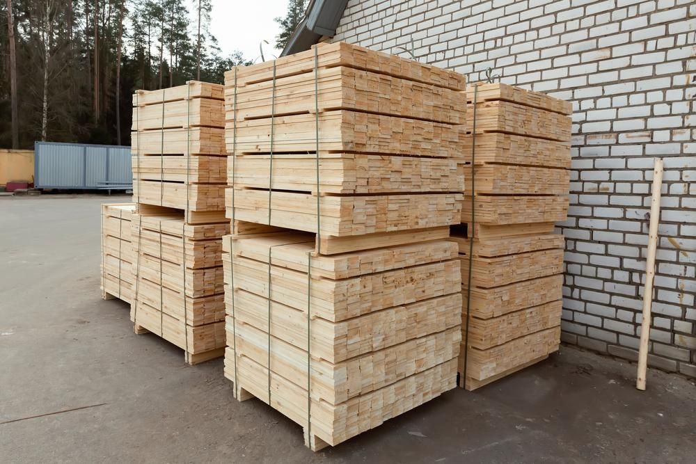 A Stack of Wooden Pallets Sitting in Front of A Brick Building — Budget Timbers in North Lismore, NSW