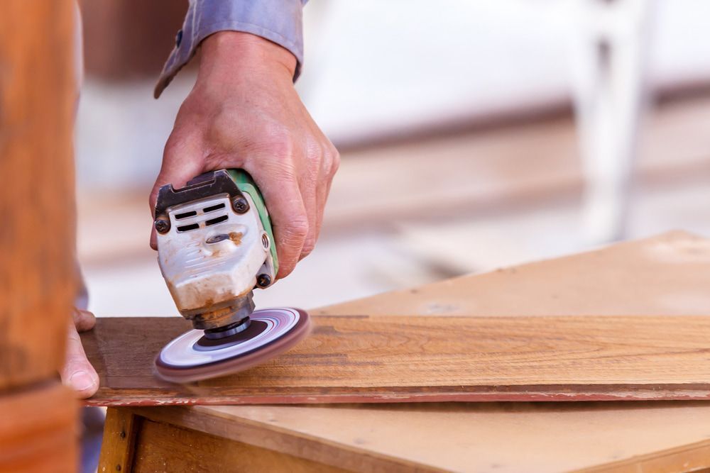 A Person Is Sanding a Piece of Wood with A Sander — Budget Timbers in Coffs Harbour, NSW