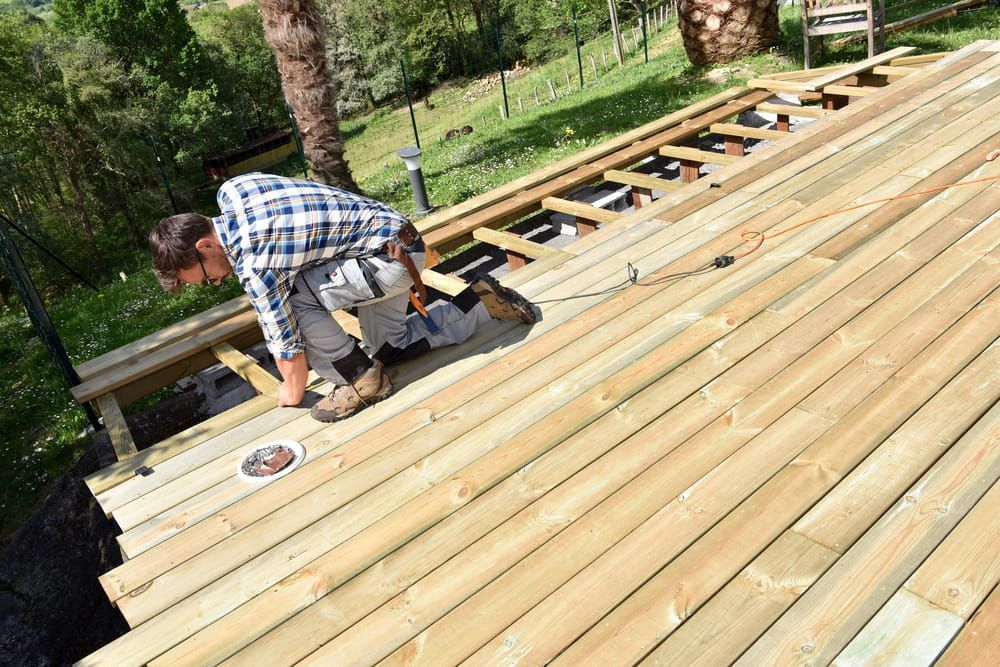 A Man Is Working on A Wooden Deck — Budget Timbers in Ballina, NSW