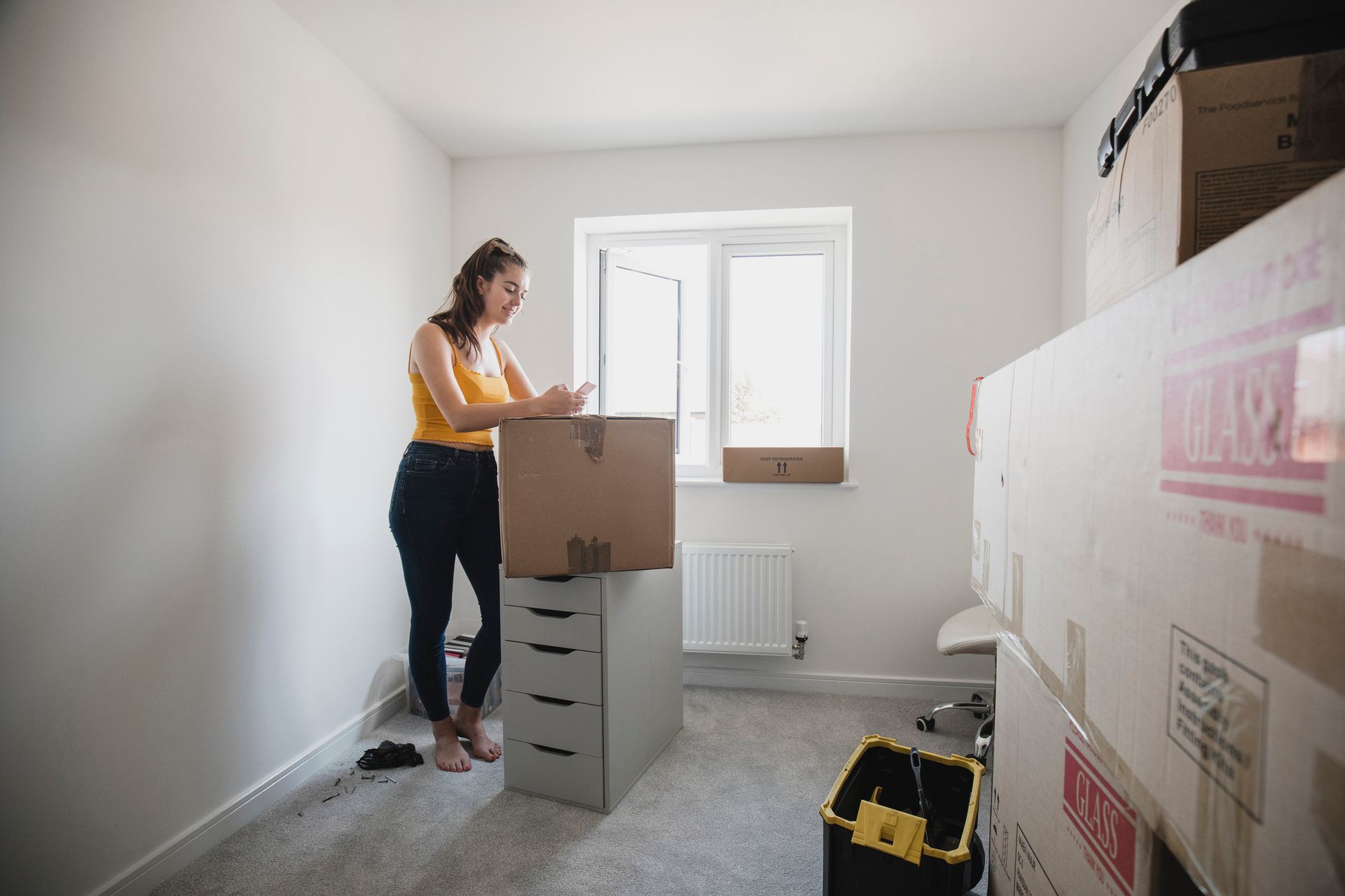 A woman is standing in a room holding a cardboard box.