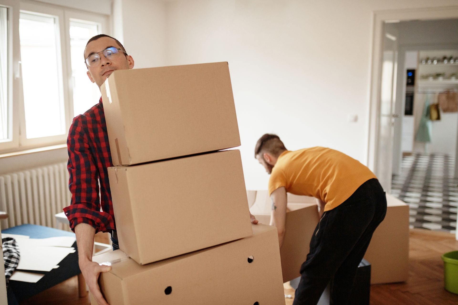 A man is carrying a stack of cardboard boxes in a living room.