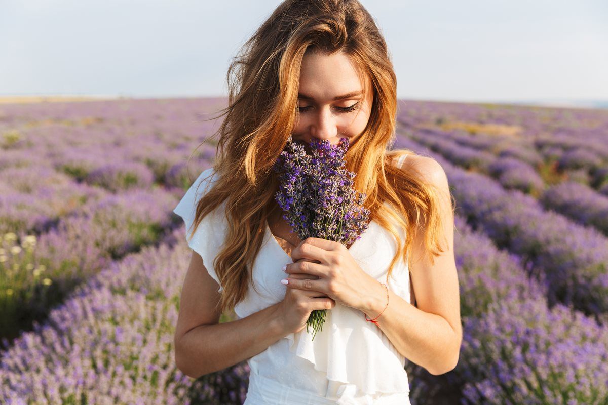 A woman is smelling flowers