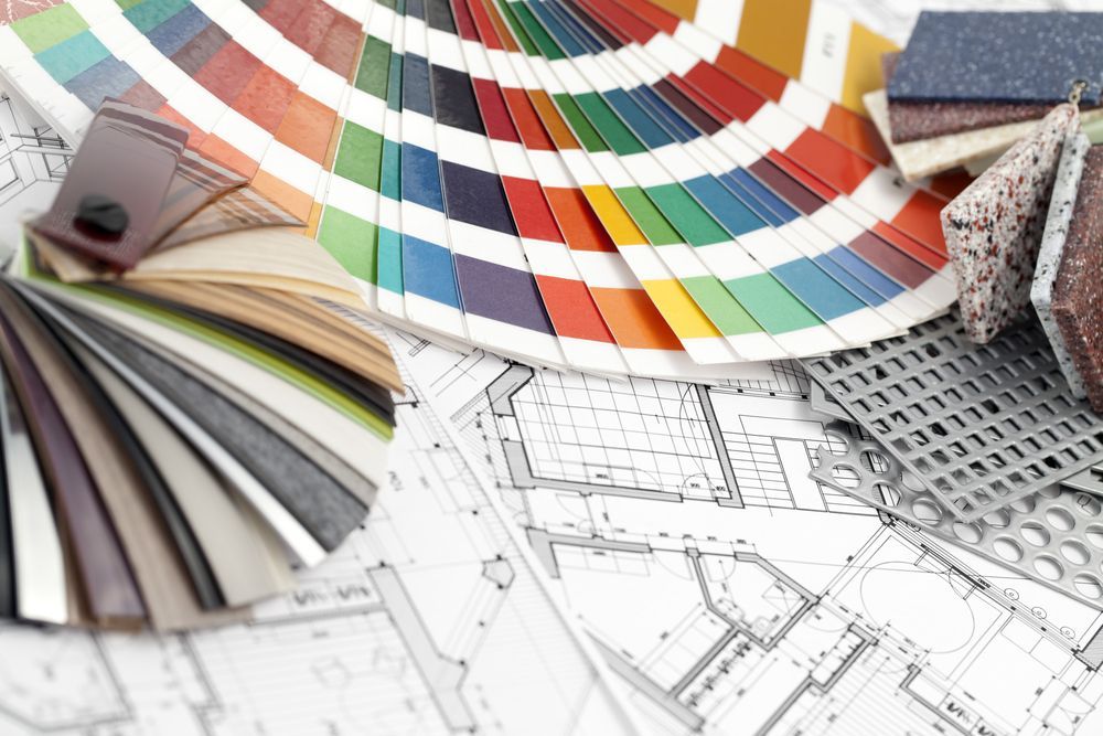 Color swatches, material samples, and a color palette fan on architectural blueprints.
