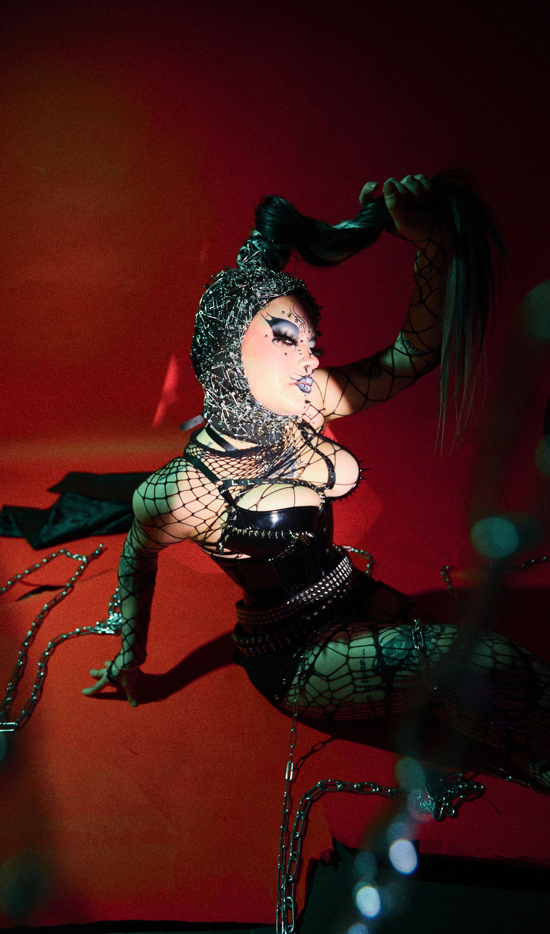 A woman in a black outfit is laying on a red couch.