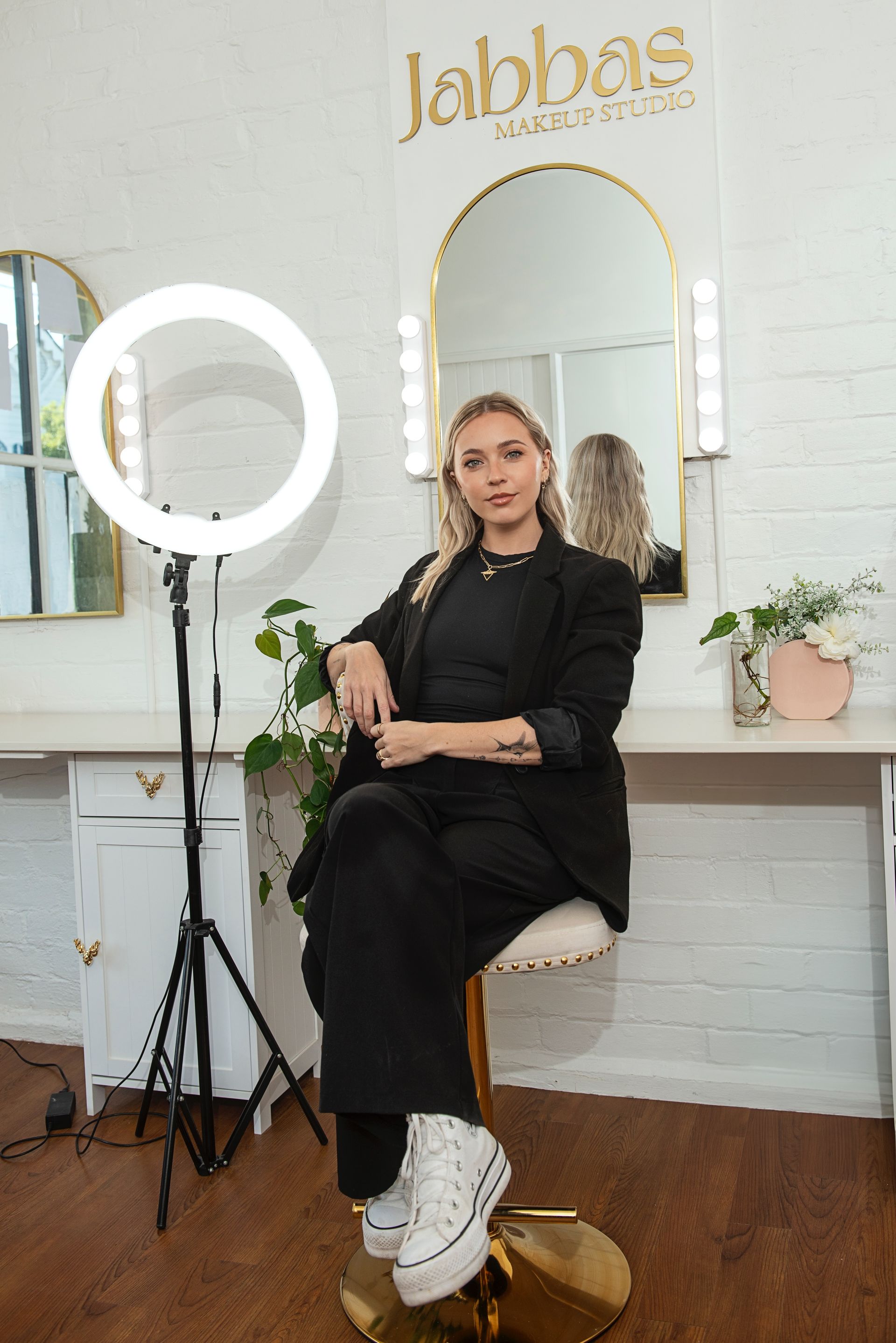 A woman is sitting on a chair in front of a mirror in a room.