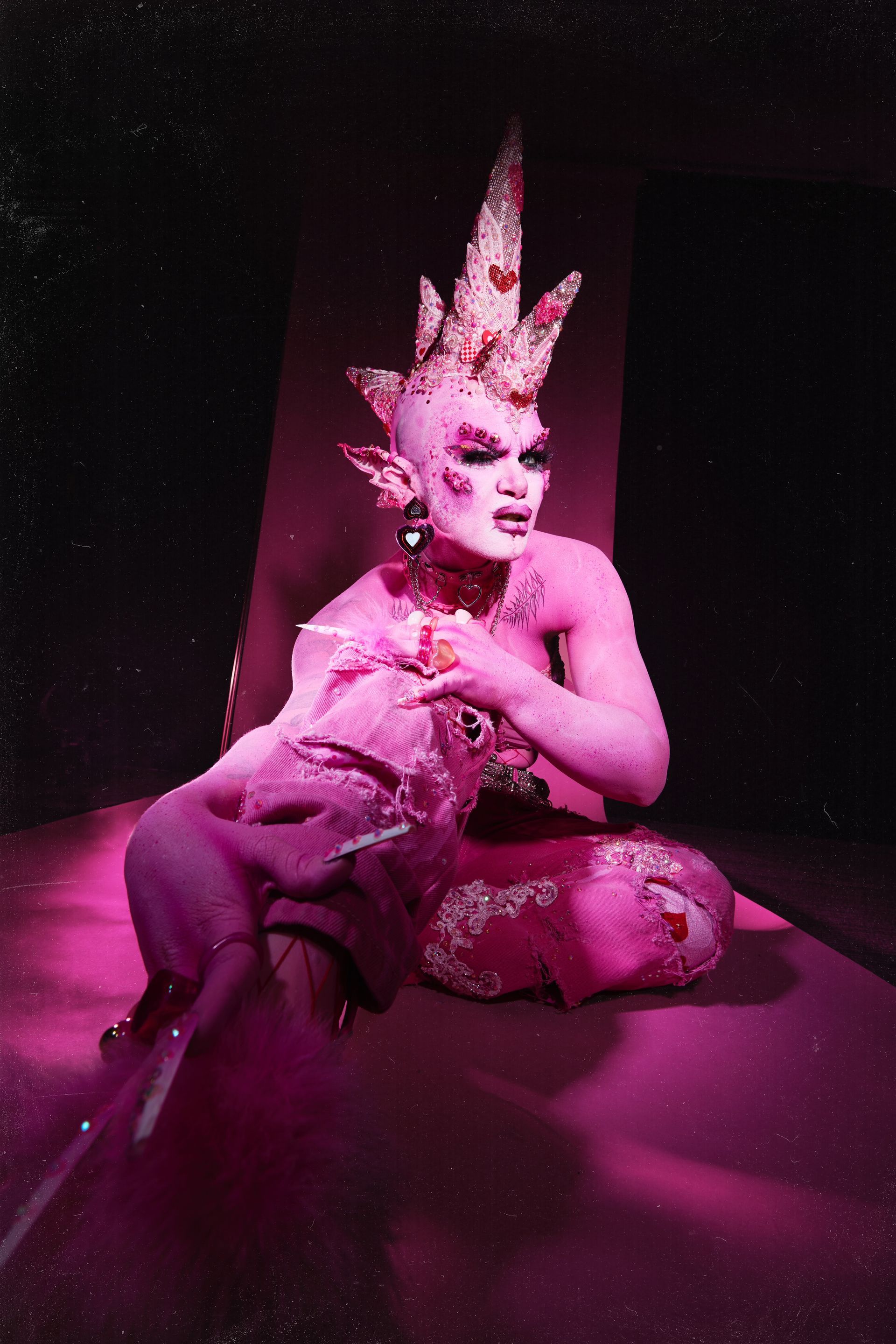 A person with pink body paint and a crown on their head