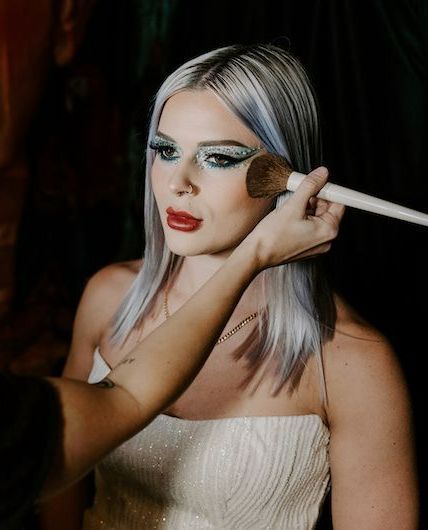 A woman is getting her makeup done by a makeup artist