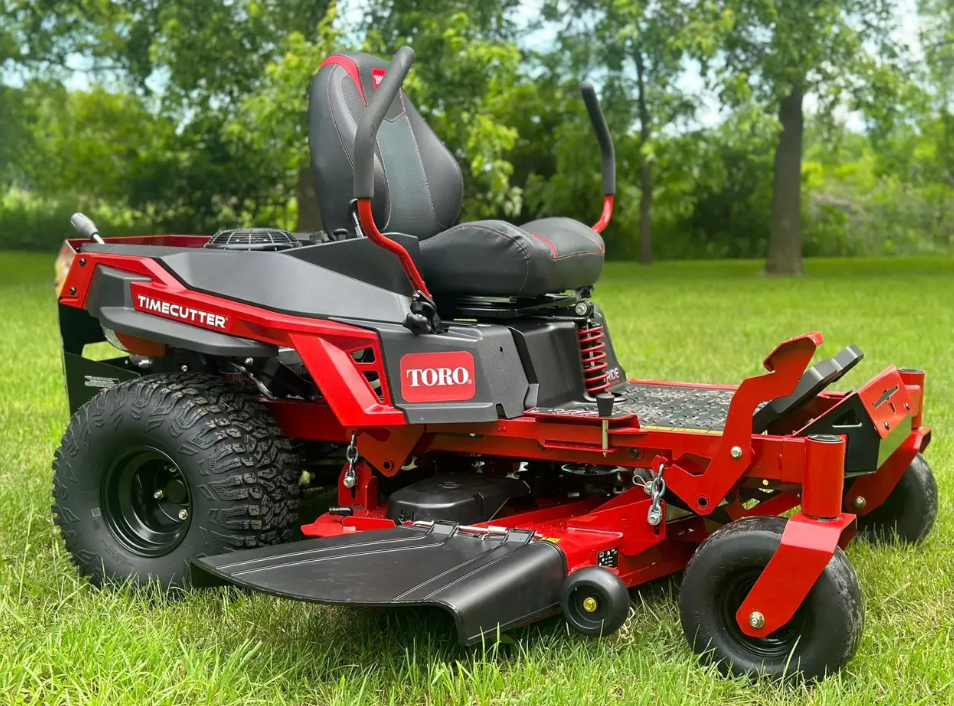 Red Toro TimeCutter zero-turn lawnmower on a grassy lawn with trees in the background.