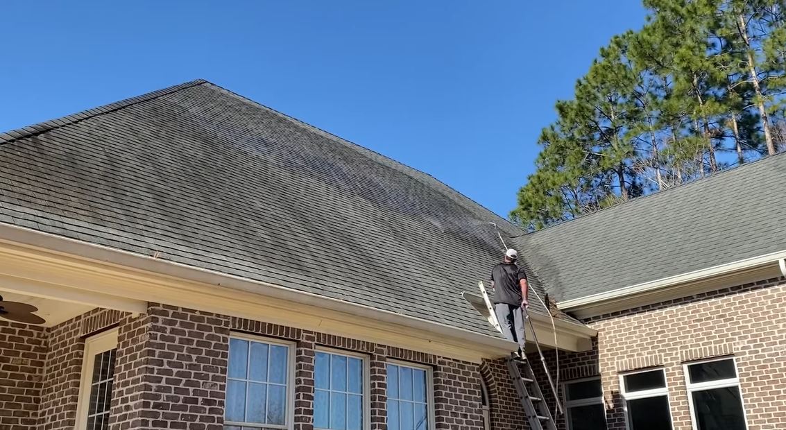 Man standing on ladder to soft wash a house in Columbia SC