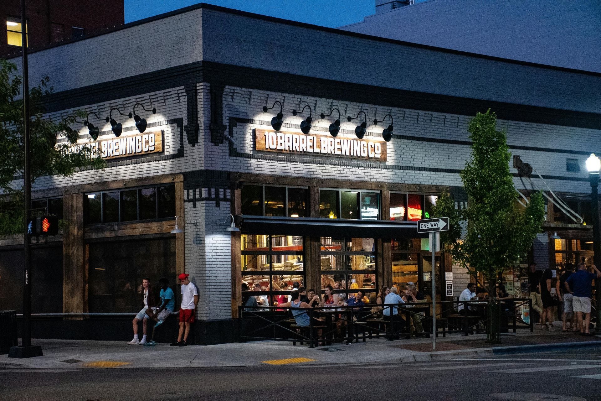 Restaurant, Bottle & Barrel, at night. People dine outside. Building has wood and bright lights.
