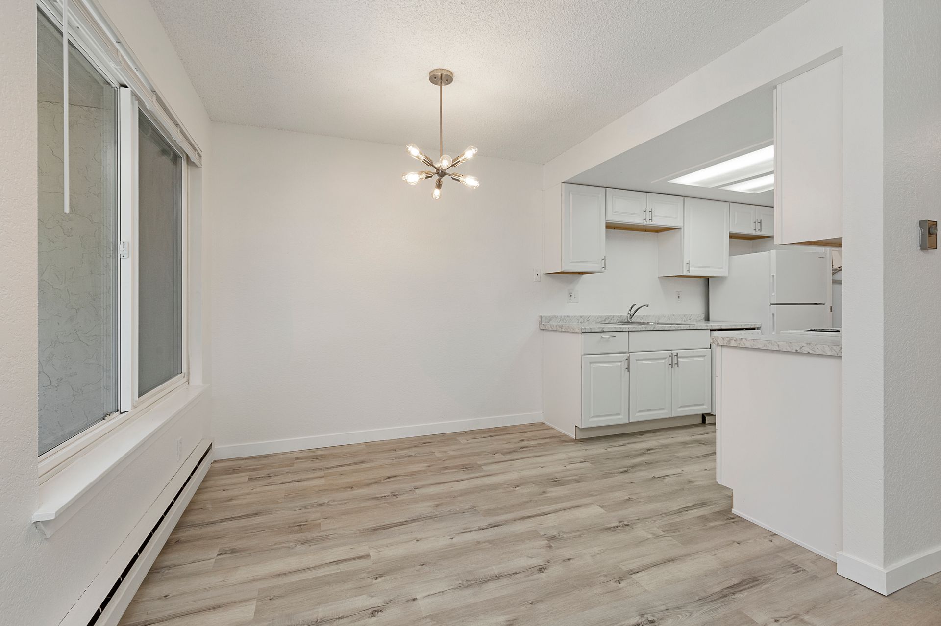 an empty room with hardwood floors and white cabinets