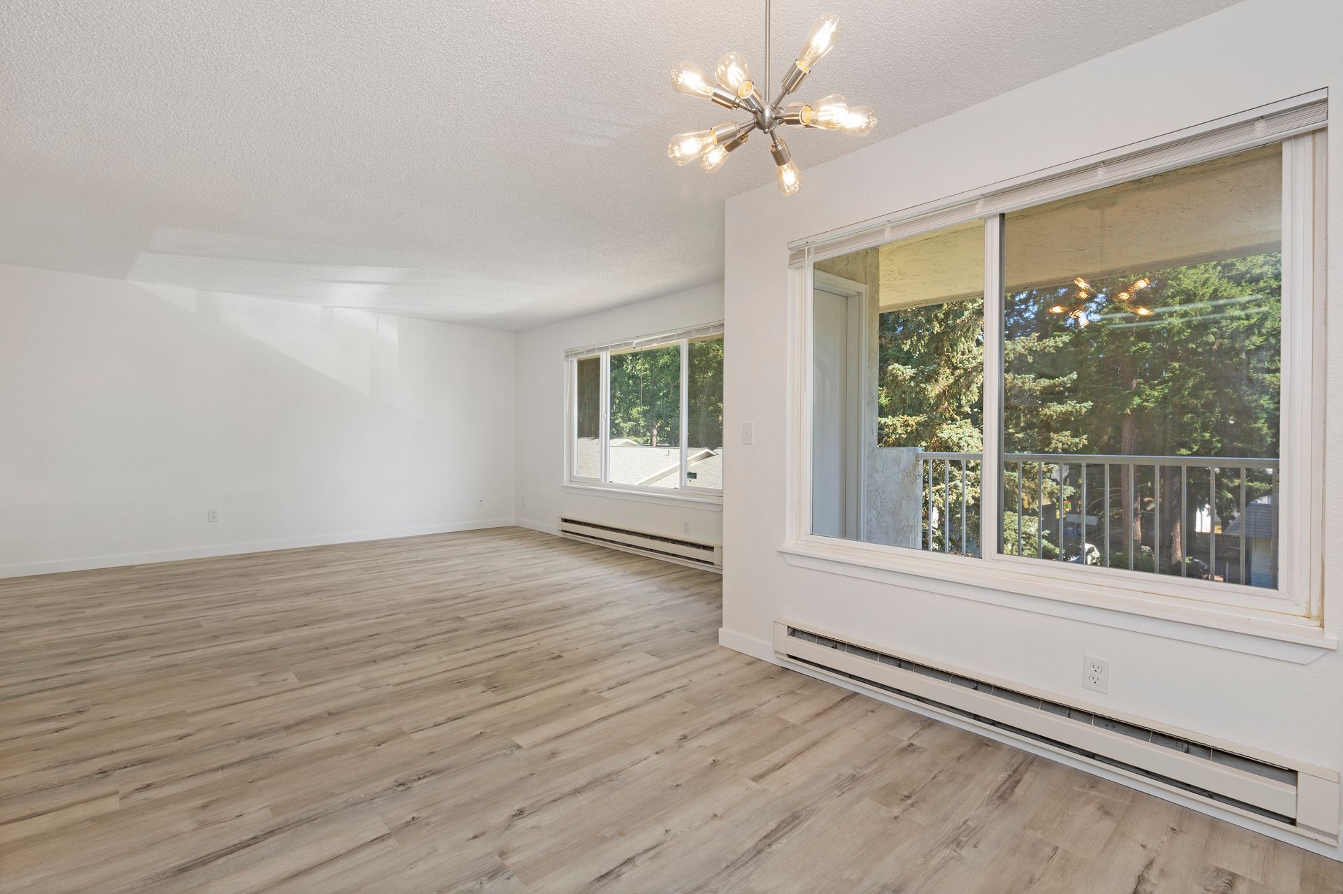 an empty living room with hardwood floors and a large window