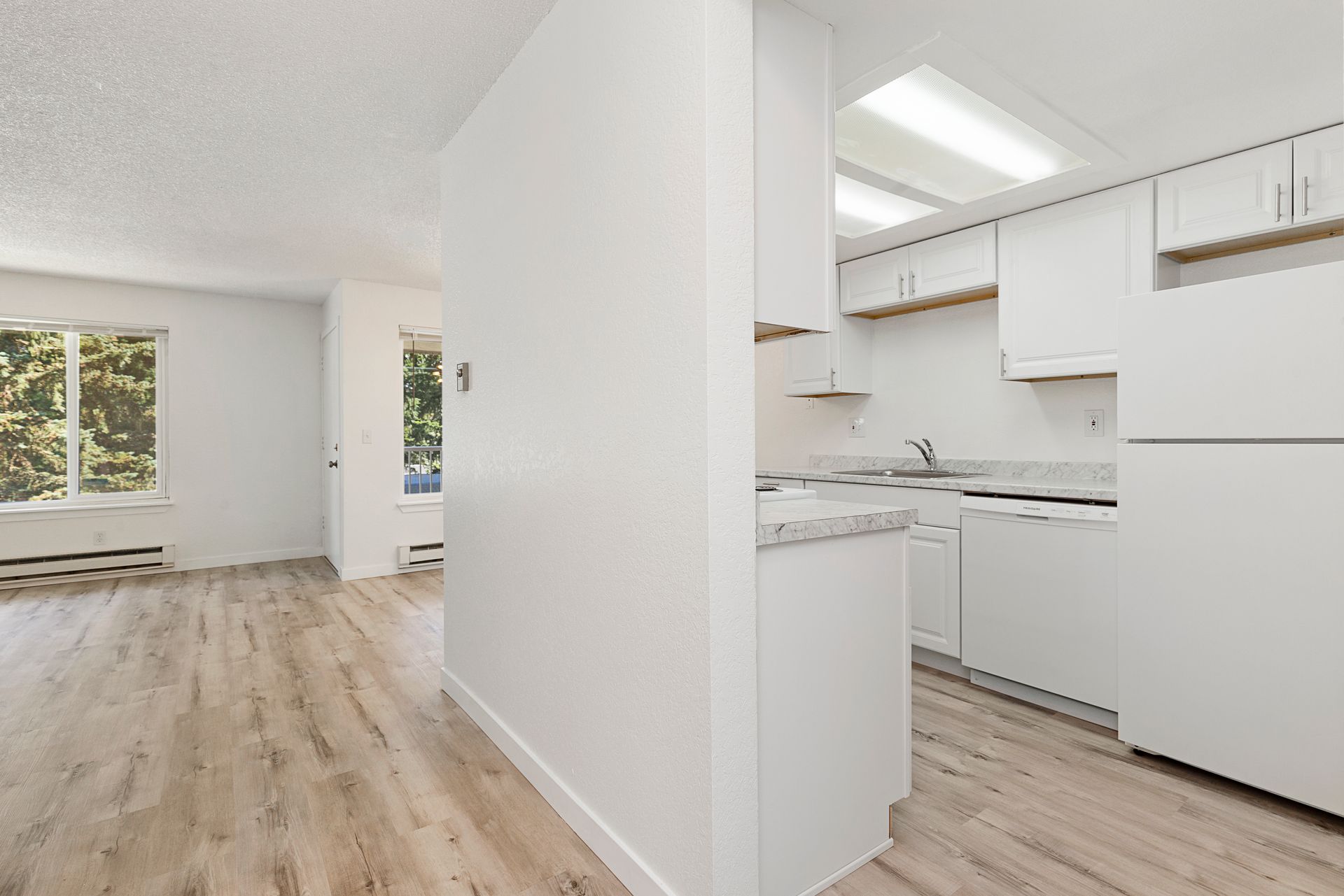 a kitchen with white cabinets , a refrigerator , and a dishwasher .