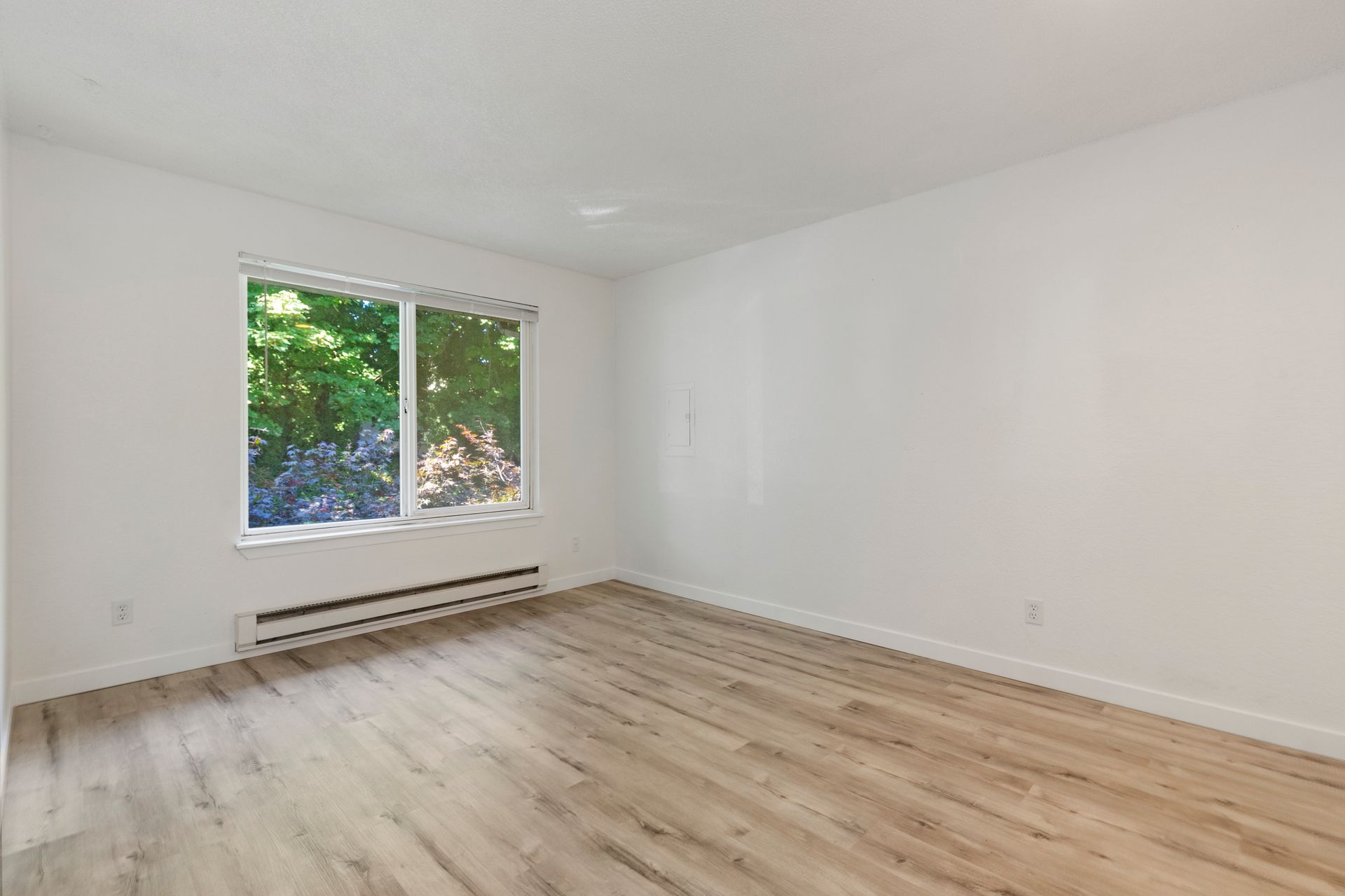 an empty living room with hardwood floors and a large window .