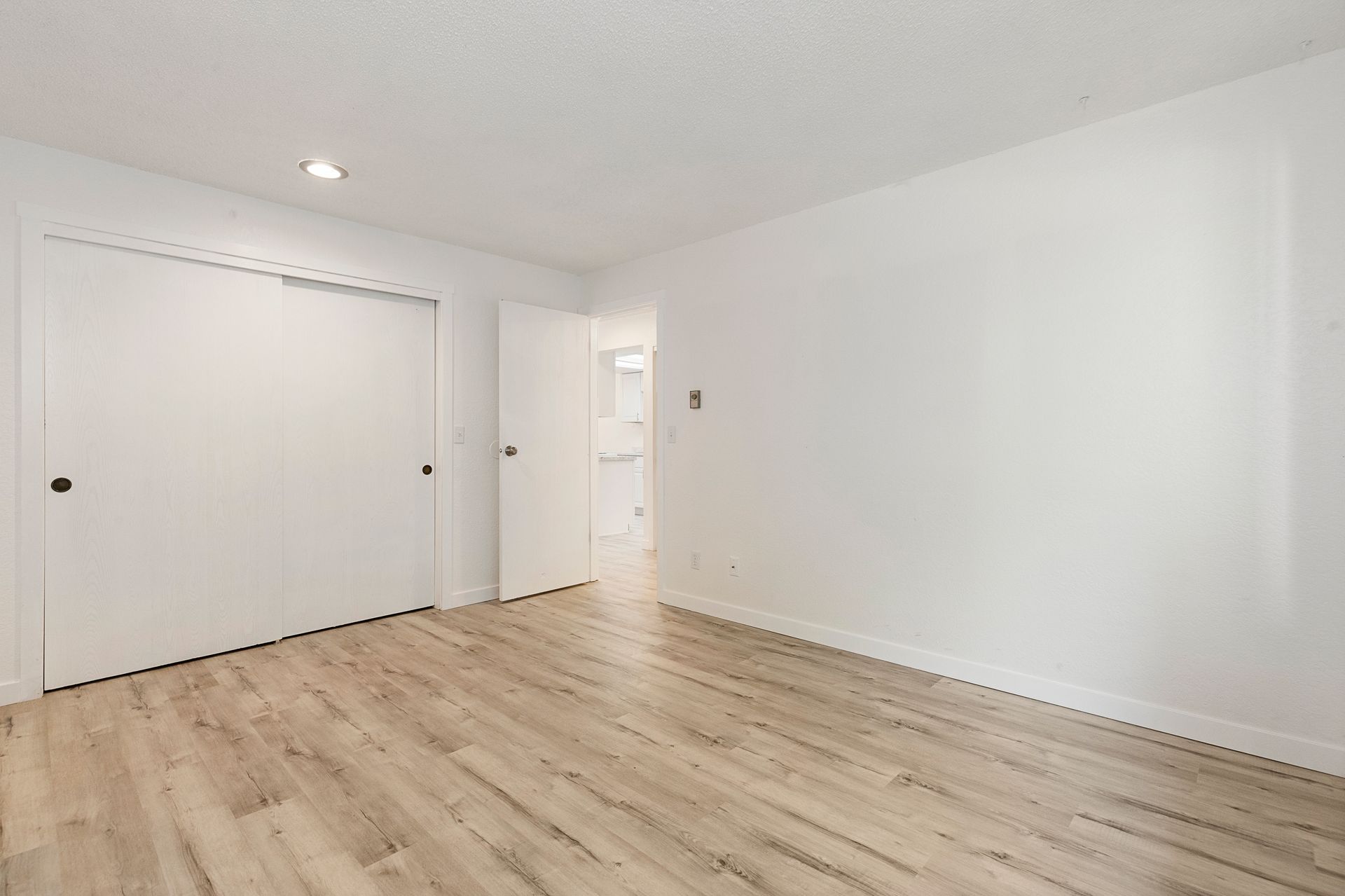 an empty bedroom with hardwood floors and white walls .