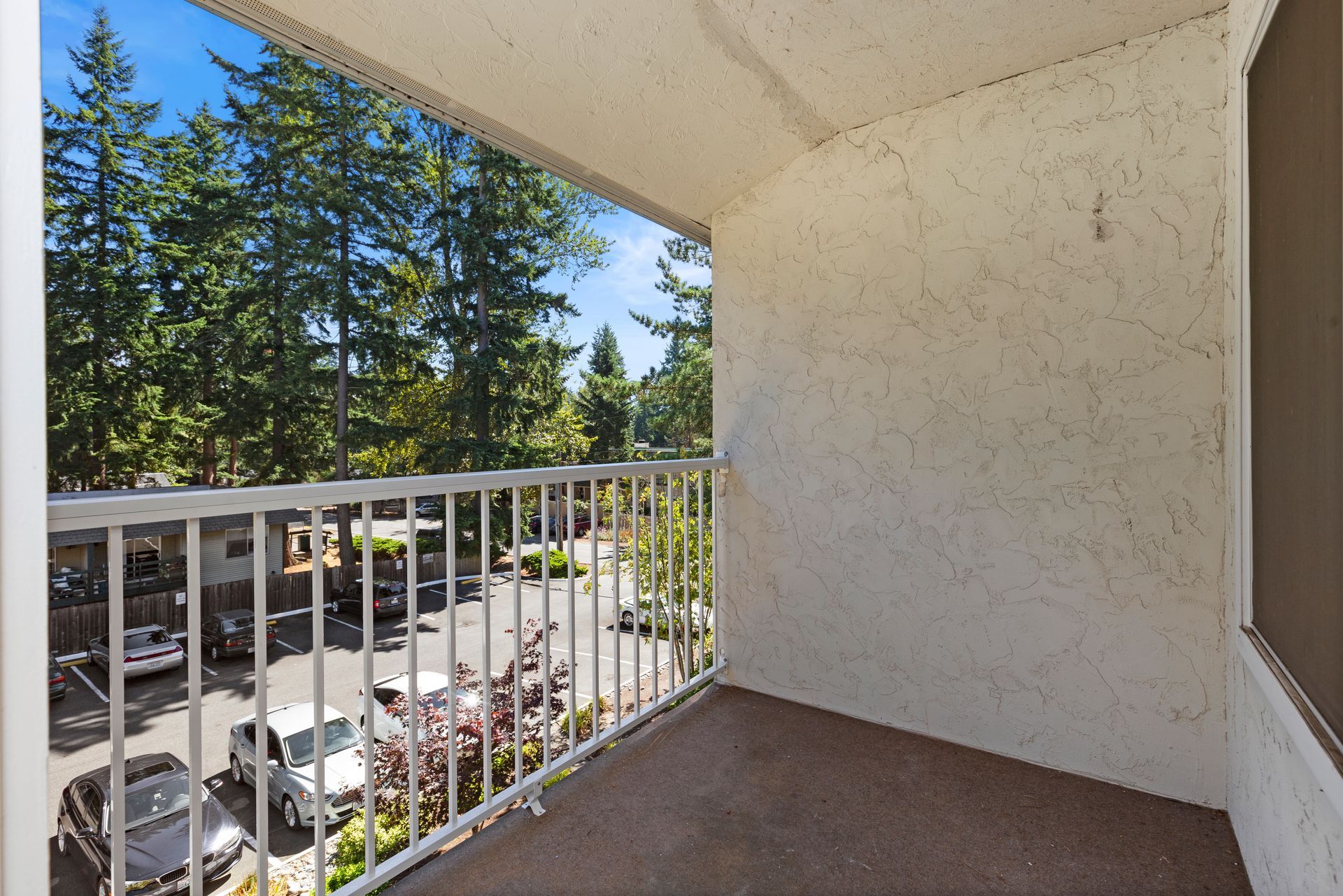 an empty balcony with a view of a street and trees