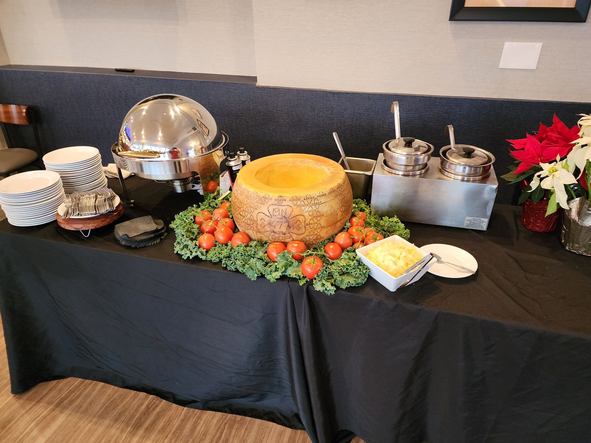 A buffet table with a large piece of cheese on top of it.