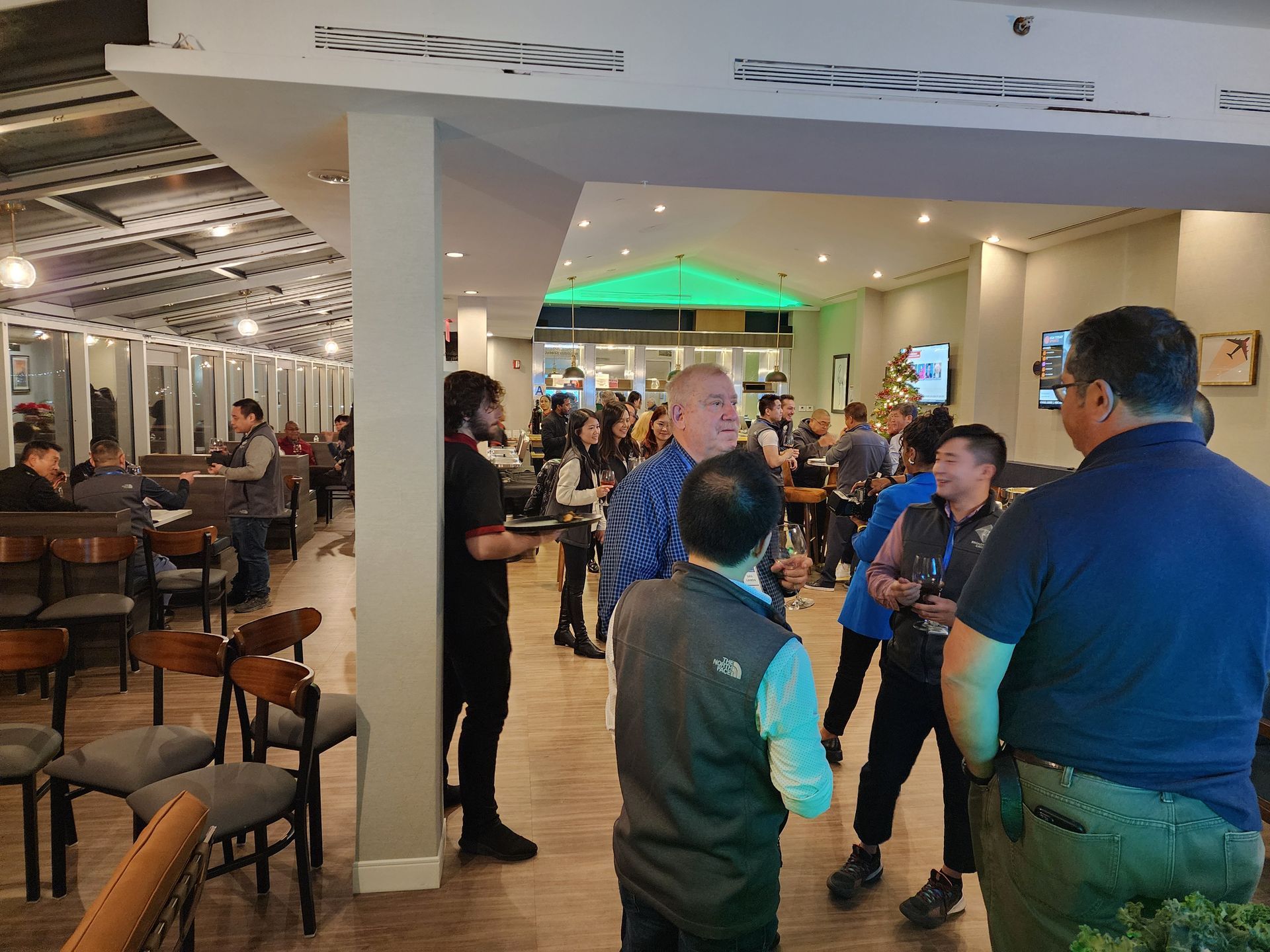 A group of people are standing in a restaurant talking to each other.
