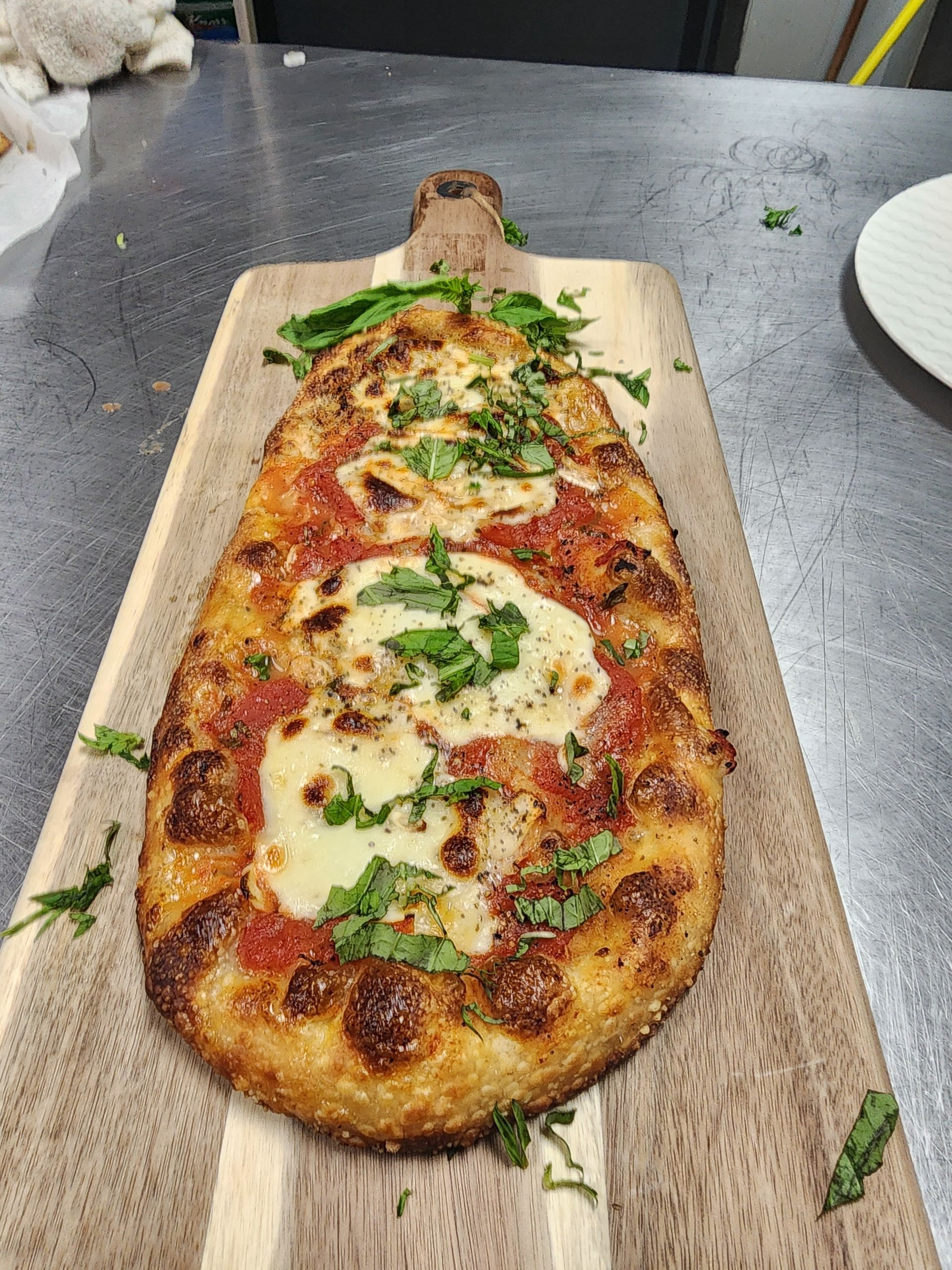 A pizza is sitting on a wooden cutting board on a table.