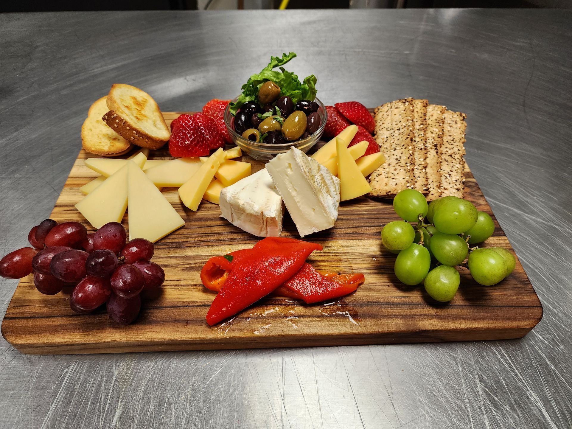 A wooden cutting board filled with cheese grapes and crackers