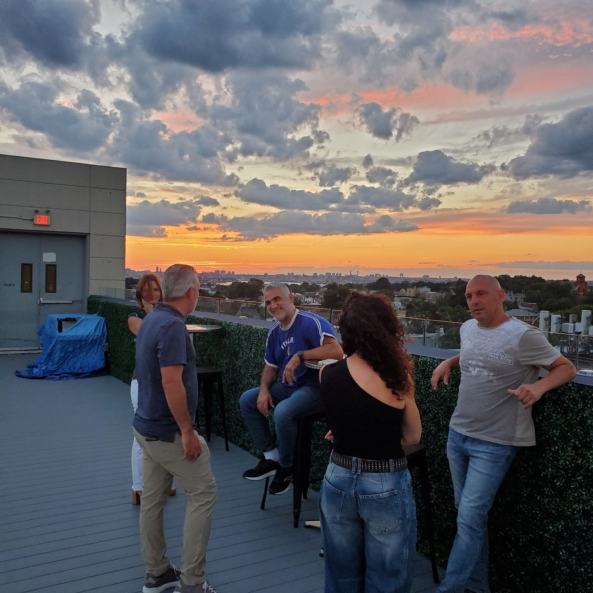 A group of people standing on a rooftop at sunset