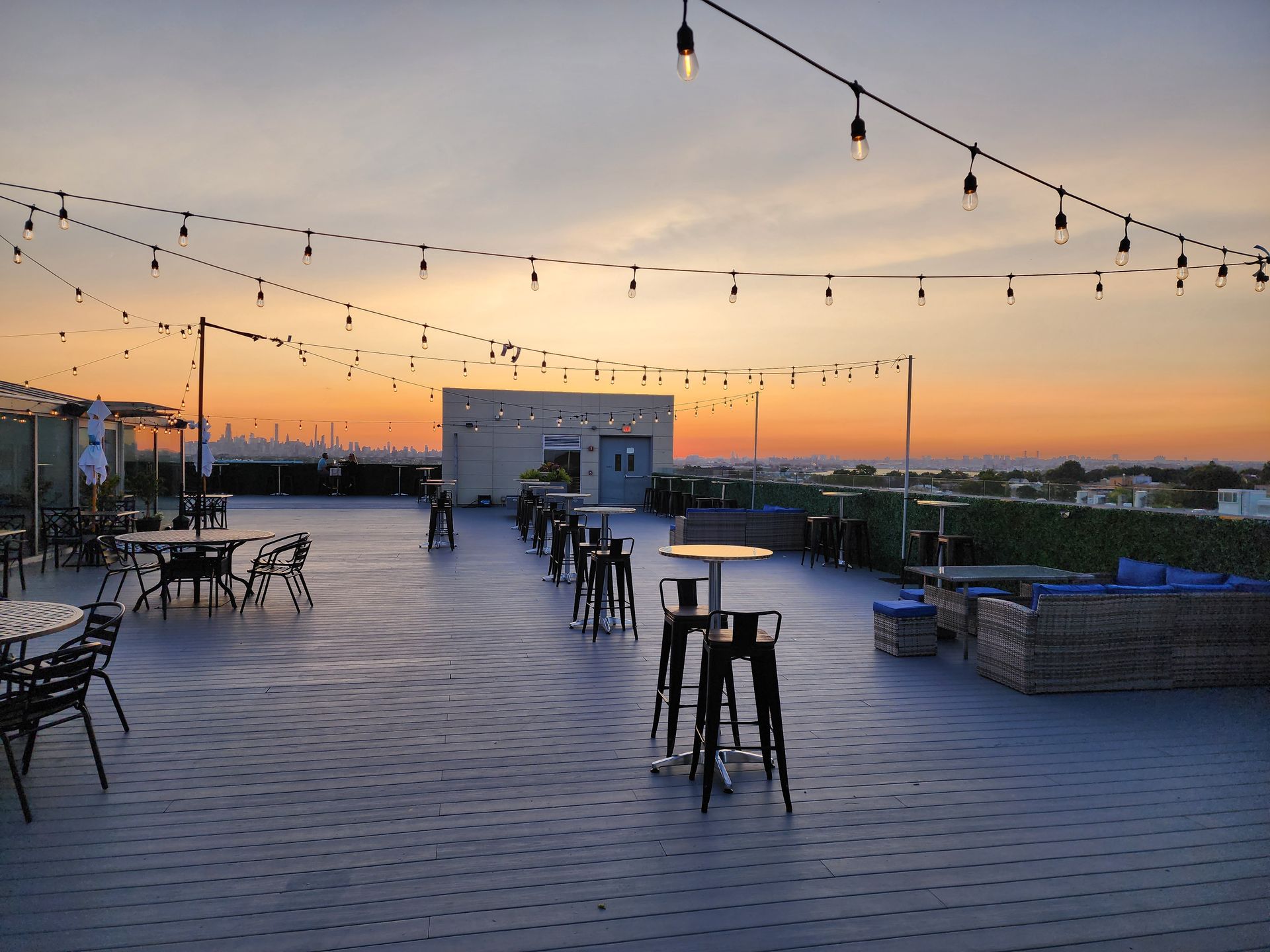 A patio with tables and chairs and a sunset in the background