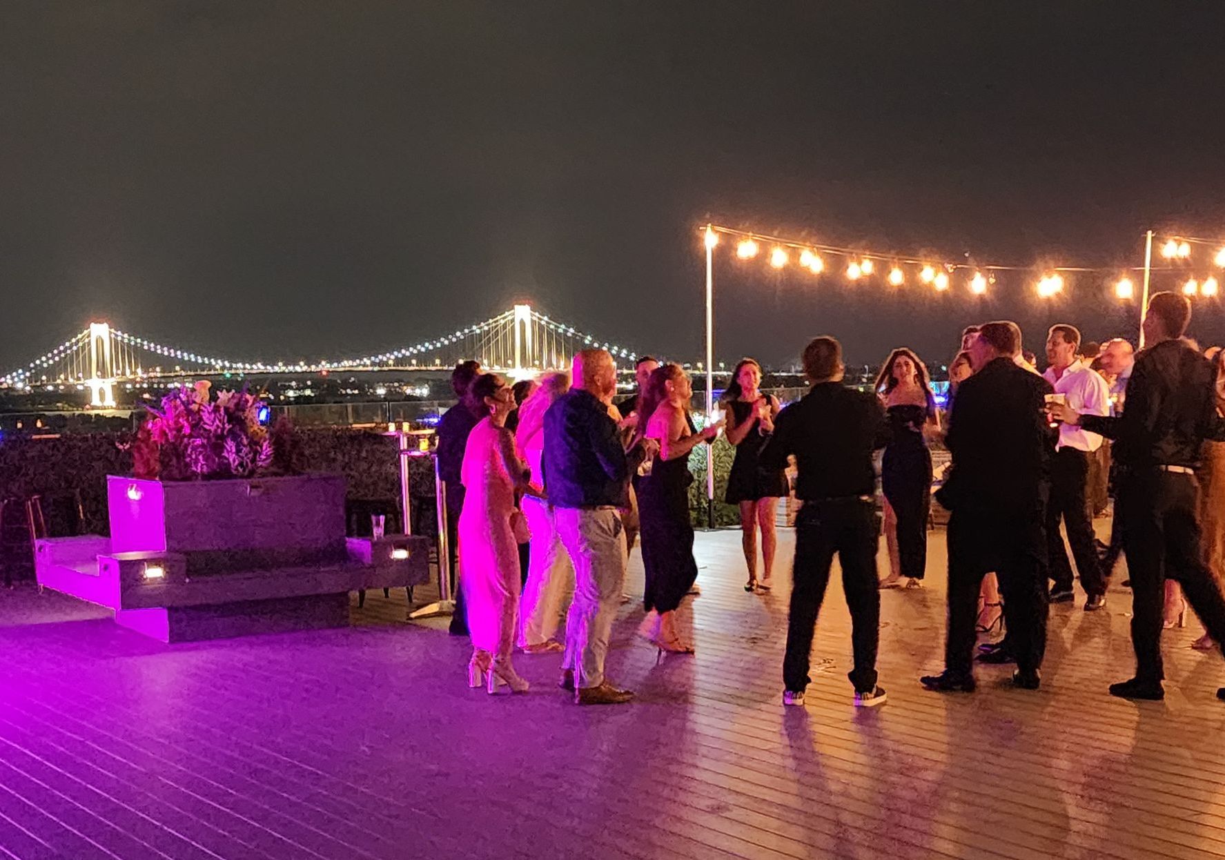 A group of people are dancing on a pier at night.