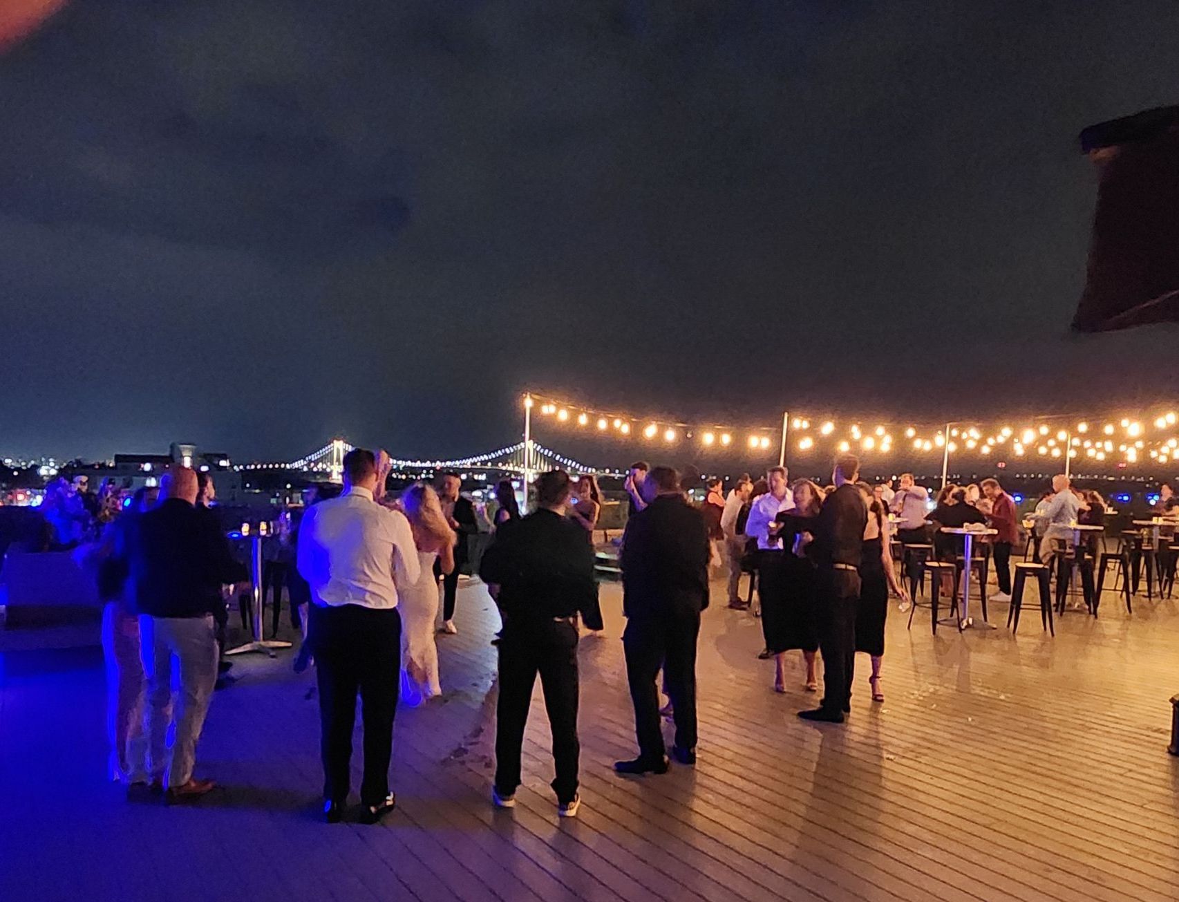 A group of people are standing on a deck at night.