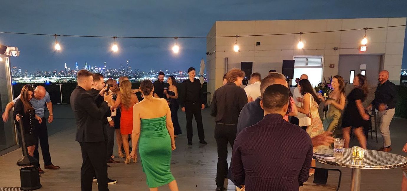 A group of people are dancing on a rooftop at a party.