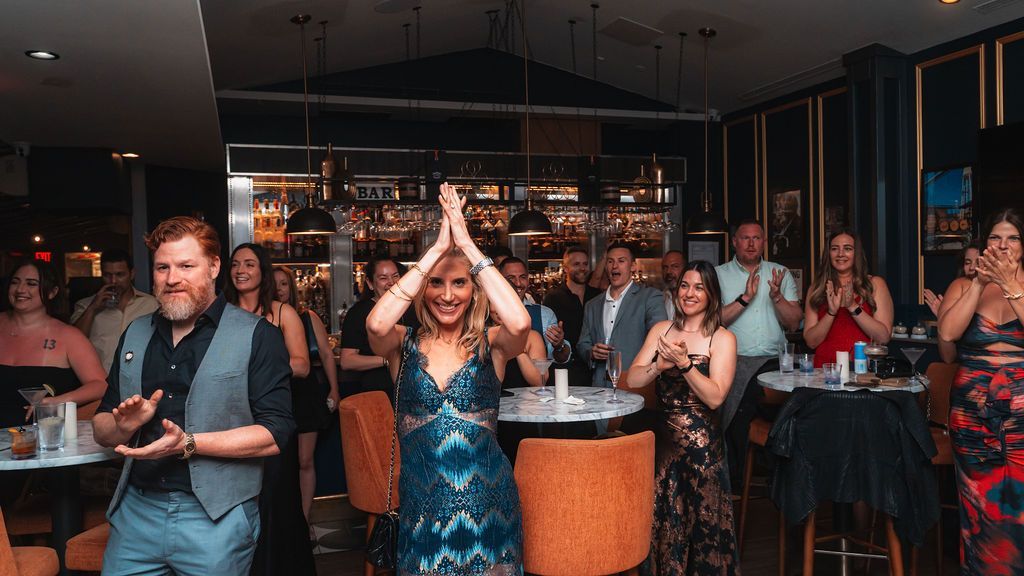 A group of people are standing in a restaurant applauding.
