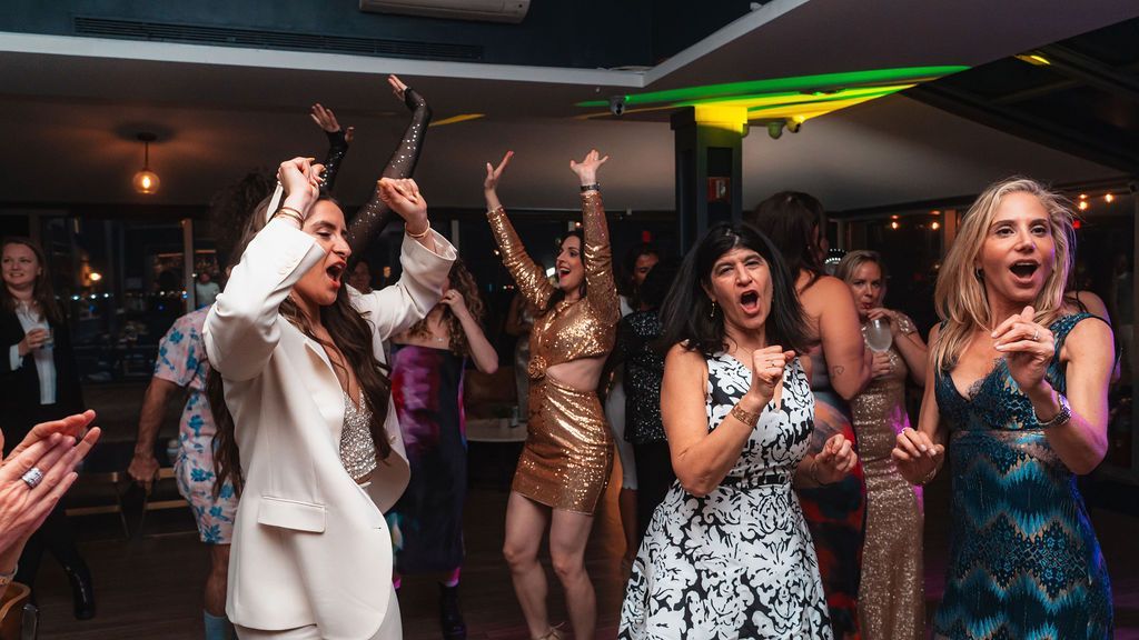 A group of women are dancing on a dance floor at a party.