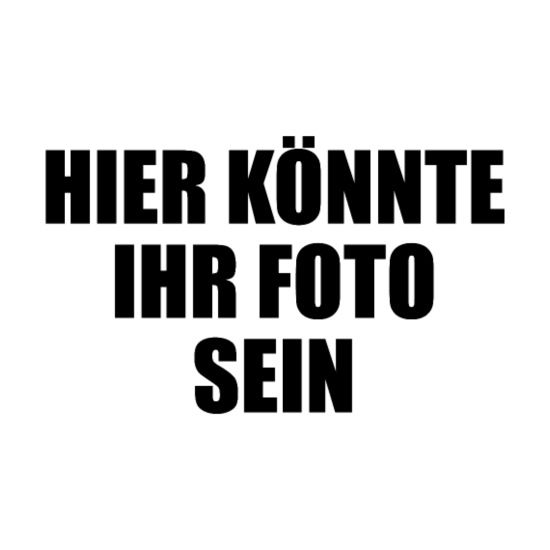 Ein Mann mit Bart steht mit verschränkten Armen vor einem Auto.