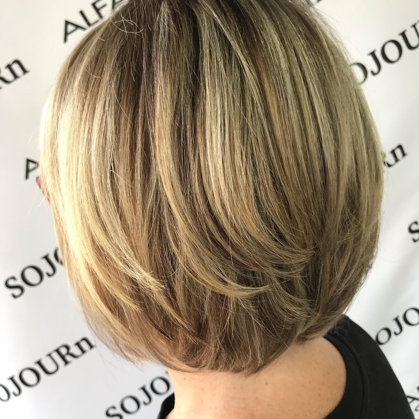 A woman in a white dress is standing in front of a brick wall