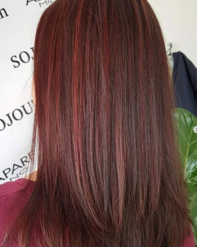 A woman with long red hair is standing in front of a sign.