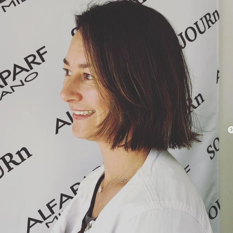 A woman stands in front of a wall that says journ