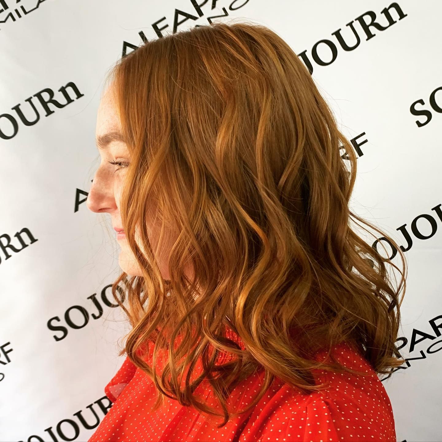 A woman with red hair is standing in front of a sign that says sojourn