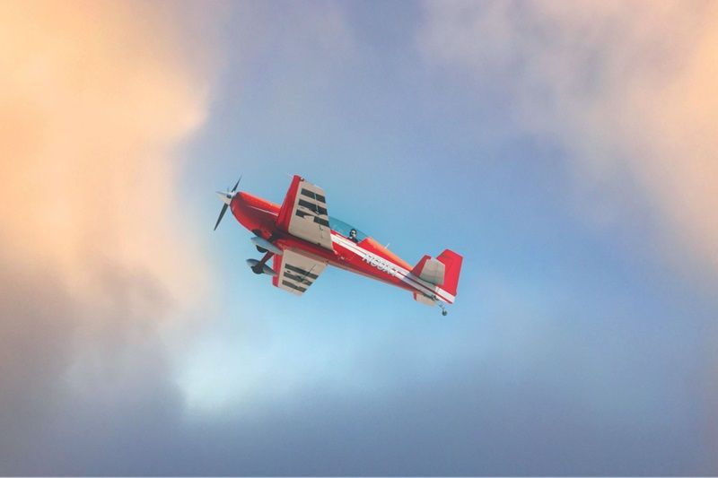 A red Sky Combat Ace plane flying through clouds. 