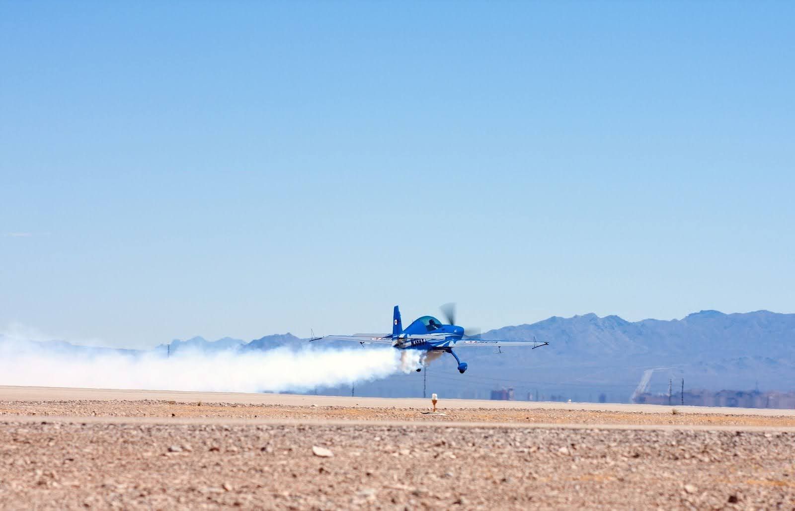 Blue stunt plane flying low to the ground