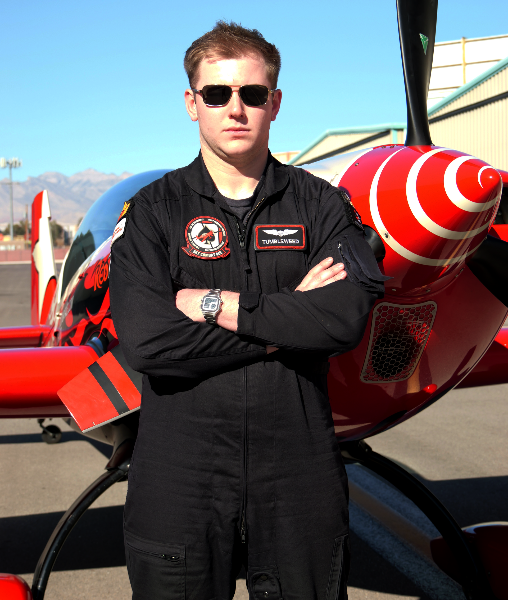 A man wearing sunglasses stands in front of a red plane