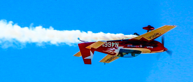 A red and yellow airplane is flying through a blue sky.