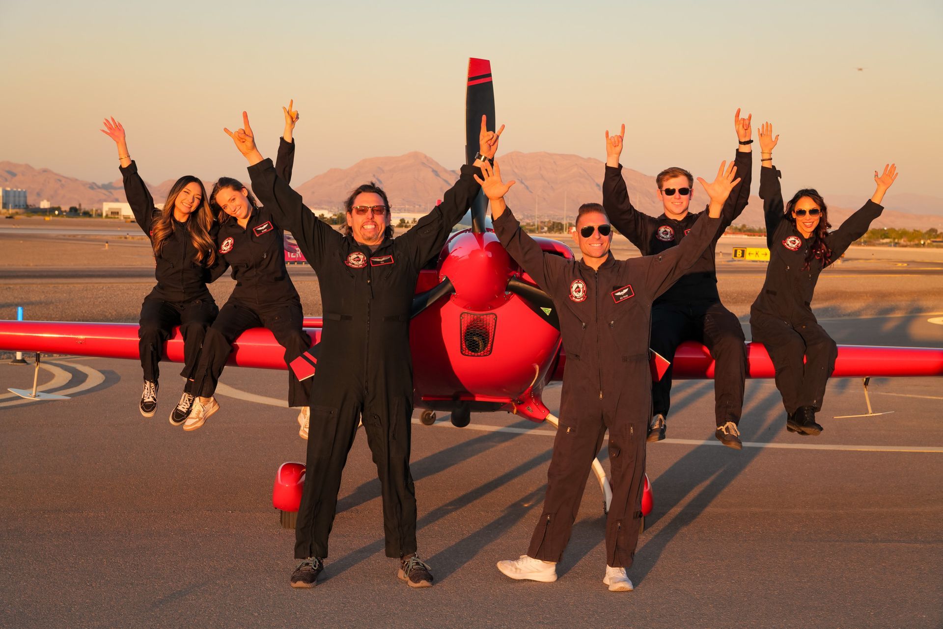 Group celebrating around the aircraft at sunset
