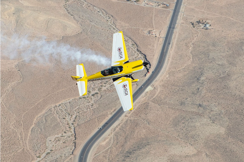 A yellow Sky Combat Ace plane flying over the desert
