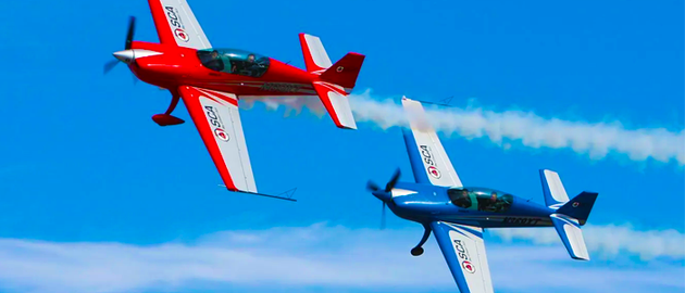 Two red and blue airplanes are flying in the sky.