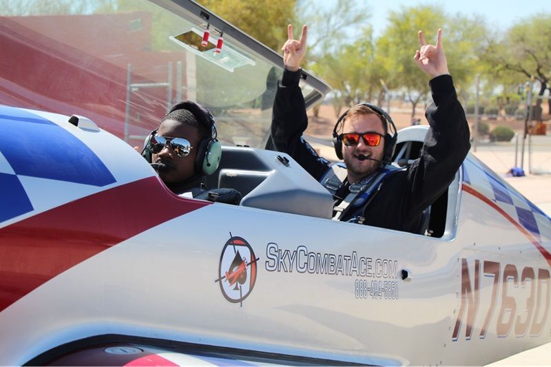 Two individuals in a cockpit of a Sky Combat Ace plane, about to take off. 
