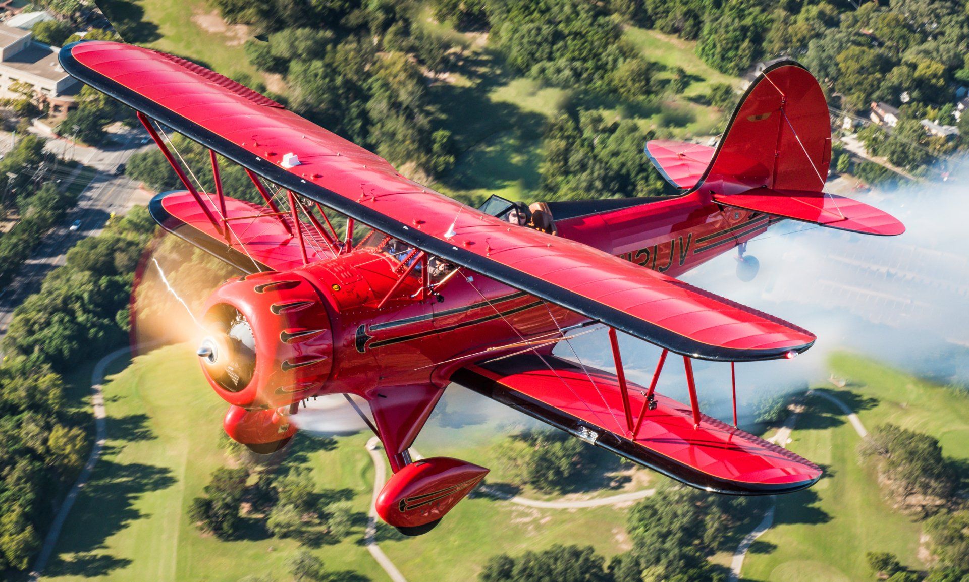 Red WACO biplane flying over a field